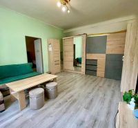 EXKLUZÍVNY PREDAJ - 2-izbový byt byt s predzáhradkou v srdci Nitry - Obývacia izba s podlahou s dreveným dekorom, sedačkou a skrinkami v 2-izbovom byte.