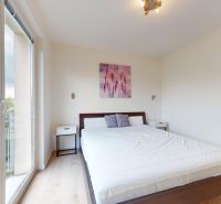 | Pekný a priestranný 3-izbový byt | 70m² |  - Svetlá spálňa s podlahou s dreveným dekorom, posteľou a balkónovými dverami v 3-izbovom byte.