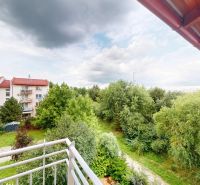 | Pekný a priestranný 3-izbový byt | 70m² |  - Výhľad z balkóna na Mečíkovej ulici v Devínskej Novej Vsi s bohatou zeleňou.