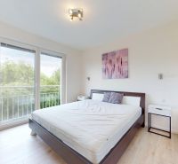 | Pekný a priestranný 3-izbový byt | 70m² |  - Spálňa s veľkou posteľou a balkónom v 3-izbovom byte s podlahou s dreveným dekorom.