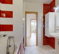 | Pekný a priestranný 3-izbový byt | 70m² |  - Kúpeľňa v 3-izbovom byte s bielymi a červenými kachličkami, umývadlom a vaňou.