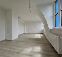 VÝNIMOČNÝ SLNEČNÝ APARTMÁN v centre mesta, UNO Poštová - Priestranná obývačka s podlahou s dreveným dekorom a veľkými oknami v 1-izbovom byte.