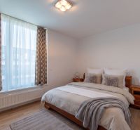 Moderný 2-izbový apartmán s parkovaním, Vila Leonardo, Bajkalská - Spálňa s veľkým oknom, dvojlôžkom a podlahou s dreveným dekorom v 2-izbovom byte.