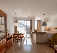 Moderný 2-izbový apartmán s parkovaním, Vila Leonardo, Bajkalská - Obývacia izba s kuchyňou v 2-izbovom byte, podlaha s dreveným dekorom, jedálenský stôl.