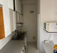 Byt na rekonštrukciu v centre Bratislavy – výborný projekt - Úzka kuchyňa v 2-izbovom byte s bielym nábytkom a kachličkami.