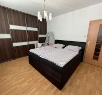 2 izbovy byt s balkónom Topoľčany  - Spálňa v 2-izbovom byte s veľkou skriňou a podlahou s dreveným dekorom.