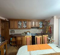 PREDAJ - Rodinný dom s veľkým pozemkom – Nitra, Lužianky  - Kuchyňa v rodinnom dome s jedálenským stolom, drevenými skriňami a dekoráciami.