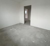 Na predaj 3 izb. byt s balkónom blízko centra - Prázdna miestnosť v 3-izbovom byte s betónovou podlahou a nedokončenými stenami.