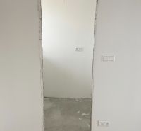 Na predaj 3 izb. byt s balkónom blízko centra - Neomietnuté dvere v 3-izbovom byte zobrazujú surovú podlahu a biele steny.