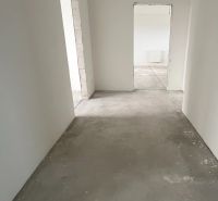 Na predaj 3 izb. byt s balkónom blízko centra - Chodba v 3-izbovom byte s betónovou podlahou a bielymi stenami.