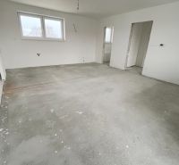 Na predaj 3 izb. byt s balkónom blízko centra - Prázdna miestnosť v 3-izbovom byte bez podlahovej krytiny a s bielymi stenami.