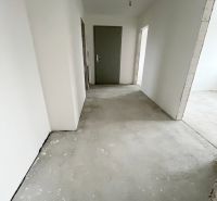Na predaj 3 izb. byt s balkónom blízko centra - Chodba v 3-izbovom byte so sivými dverami a neukončenou podlahou.