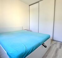 MODERNÝ 2i byt, POD VINICOU, LOGGIA, PARKING, Nové Mesto - Spálňa v 2-izbovom byte s posteľou, nočným stolíkom a vstavanou skriňou.