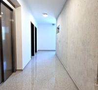 MODERNÝ 2i byt, POD VINICOU, LOGGIA, PARKING, Nové Mesto - Chodba s výťahom, schodiskom a betónovou stenou v bytovom dome.