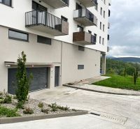 Prenájom kancelárskych / obchodných priestorov s terasou - Bytový dom s balkónmi, zeleňou a parkovaním v Považskej Bystrici, kancelárie v pozadí.
