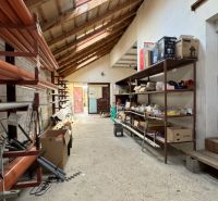 NA PREDAJ rodinný dom/polyfunkcia Komjatice  - Skladový priestor v rodinnom dome s regálmi a stavebným materiálom.