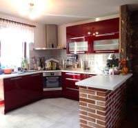 ZNÍŽENÁ CENA Bungalov s veľkým potenciálom Borský Mikuláš - Kuchyňa v rodinnom dome s lesklými červenými skrinkami a tehlovým pultom.