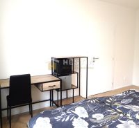 Krásny, moderne zariadený 1 izbový byt na prenájom - Izba s posteľou, pracovným stolom, čiernou stoličkou a podlahou s dreveným dekorom.