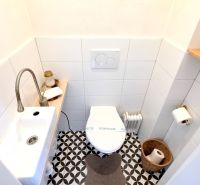 ŠTÝLOVÝ 2i BYT, REKONŠTRUKCIA, BALKÓN, KLÍMA, Murgašová ulica - Toaleta s bielymi obkladmi a vzorovanou podlahou v 2-izbovom byte.
