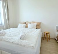ŠTÝLOVÝ 2i BYT, REKONŠTRUKCIA, BALKÓN, KLÍMA, Murgašová ulica - Svetlá spálňa s posteľou, bielymi stenami, komodou a podlahou s dreveným dekorom.