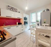 NOVÁ CENA-NA PREDAJ pekný 3ibyt Prievidza-Necpaly - Kuchyňa v 3-izbovom byte s bielym nábytkom a podlahou s dreveným dekorom.
