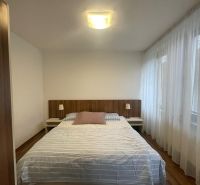 PRENÁJOM – 2-izbový veľkometrážny byt – Mostná, Nitra - Spálňa s posteľou, bielymi závesmi a podlahou s dreveným dekorom v 2-izbovom byte.