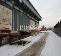Na predaj výrobná hala v meste Humenné - Zasnežené obchodné priestory Na podskalku v Humennom s priemyselnou fasádou a červenou dodávkou.