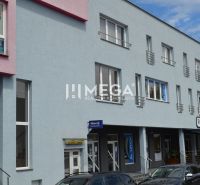 PRENÁJOM obchodného priestoru v centre Humenného (74 m2) - Obchodné priestory na ulici Osloboditeľov v Humennom s farebnou fasádou a autami v popredí.