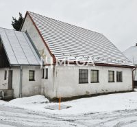 Predaj budovy v obci Zboj - Snehom pokryté obchodné priestory v obci Zboj s tradičnou architektúrou a strechou.