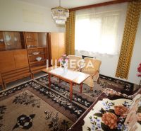 REZERVOVANÝ - Pôvodný rodinný dom v obci Dlhé nad Cirochou - Izba v rodinnom dome s kobercom, sedačkou, stolom a vitrínovou skriňou.