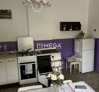 Znížena cena domu na Jesenského ulici v Snine - Jedáleň v Rodinnom dome s fialovou stenou, kvetinovým dekórom a kuchynskými spotrebičmi.