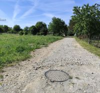 Na predaj pozemky vo Veľkom Šariši - Prírodné prostredie vo Veľkom Šariši, viditeľná štrková cesta a zeleň.