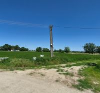 Stavebný pozemok v pokojnej časti obce Veselé - Pozemky - bývanie na Veselé pri Veselom s elektrickým stĺpom uprostred zelenej krajiny.