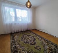 Na predaj priestranný 3-izbový byt s garážou v Nitre – Chrenová - Izba so vzorovaným kobercom, podlahou s dreveným dekorom a veľkým oknom.