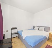 Na predaj 5-izbový rodinný dom v Malých Dvorníkoch - Spálňa v rodinnom dome so sivou posteľou, fialovými závesmi a podlahou s dreveným dekorom.