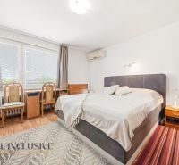 Na predaj 5-izbový rodinný dom v Malých Dvorníkoch - Spálňa v rodinnom dome s posteľou, dvoma stoličkami a podlahou s dreveným dekorom.