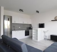 Moderný 2-izbový byt na prenájom-Hviezdoslavov–parkovanie,klimatizácia - Kuchyňa v 2-izbovom byte s bielymi skrinkami a podlahou s dreveným dekorom.