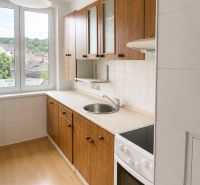 Na predaj: 3-izbový byt v meste Krásno nad Kysucou - Kuchyňa 3-izbového bytu s dverami na balkón a podlahou s dreveným dekorom.