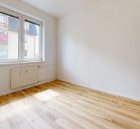 1-izbový byt 39.7m2, ul. Cukrovarská | Trenčianská Teplá - Svetlá miestnosť v 1-izbovom byte s podlahou s dreveným dekorom a veľkým oknom.