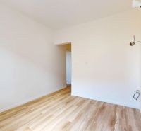 1-izbový byt 39.7m2, ul. Cukrovarská | Trenčianská Teplá - Izba v 1-izbovom byte s bielymi stenami a podlahou s dreveným dekorom.