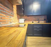 | Srdce Mesta | 2 Izb. byt | ORBIS |  70 m2 - Kuchyňa v 2-izbovom byte s tehlovou stenou a podlahou s dreveným dekorom.