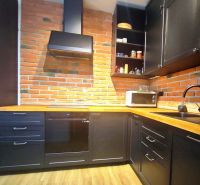 | Srdce Mesta | 2 Izb. byt | ORBIS |  70 m2 - Kuchyňa v 2-izbovom byte s tehlovou stenou a podlahou s dreveným dekorom.