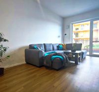 | Srdce Mesta | 2 Izb. byt | ORBIS |  70 m2 - Obývacia izba v 2-izbovom byte s pohovkou, rastlinou a podlahou s dreveným dekorom.