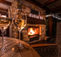 PREDANÉ !!!!Na predaj penzión – Nová Lesná, Vysoké Tatry O600BD - Dva poháre vína na stole pri krbe v interiéri Hotely a penzióny.