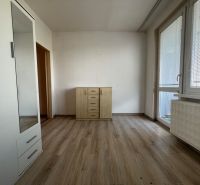 Na predaj 1-izbový byt s loggiou - Žiar nad Hronom, M. Chrasteka 1B718 - Izba v 1-izbovom byte s podlahou s dreveným dekorom a komodou.