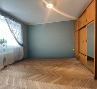 Na predaj 3-izbový byt s loggiou – Žiar nad Hronom, ul. D. Hrdinov - Izba s podlahou s dreveným dekorom, šatníkovou skriňou a záclonami v 2-izbovom byte.