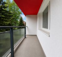 Na prenájom 2-izbový byt s veľkou loggiou v obci Slovenská Ľupča - Balkón z 2-izbového bytu s červeným stropom a zábradlím so sklom.