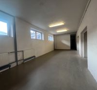 Sklad + kancelárie 1349 m² logistický objekt s rampami -Banská Bystria - Dlhá miestnosť s bielymi stenami, oknami a liatinovými radiátormi v skladoch a halách.