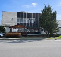 Komerčné priestory pri hlavnej ceste s parkoviskom -Žiar nad Hronom - Exteriér gastro priestorov v Žiari nad Hronom, obklopený stromami a zaparkovanými autami.