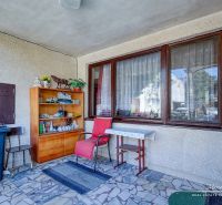 6-izbový rodinný dom v obci Biely Kostol - V rodinnom dome je veranda so stoličkou, stolíkom, policami a dekoráciami.